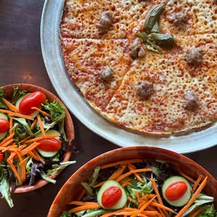 A cheese and sausage bar pie beside two garden salads with tomatoes and carrots.