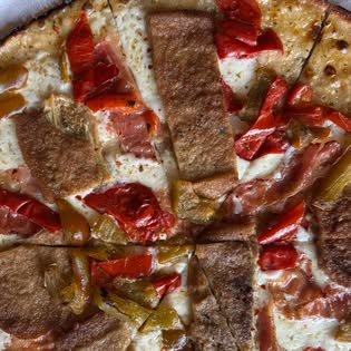 A white bar pie topped with roasted red peppers and strips of sausage.